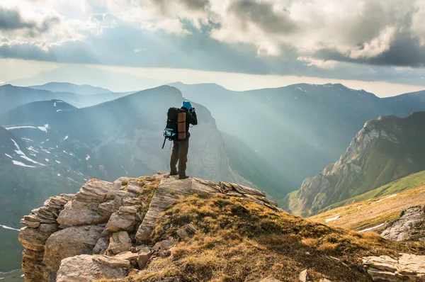 Jeune homme debout sur un rocher et regardant une belle montagne — Photo