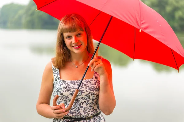 Junge Dame mit rotem Regenschirm in Teichnähe — Stockfoto