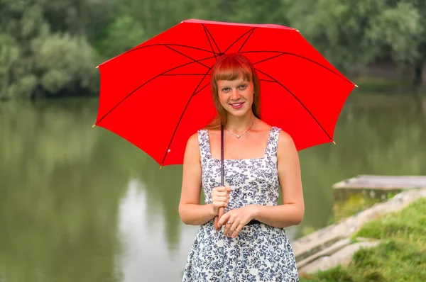 Junge Dame mit rotem Regenschirm in Teichnähe — Stockfoto