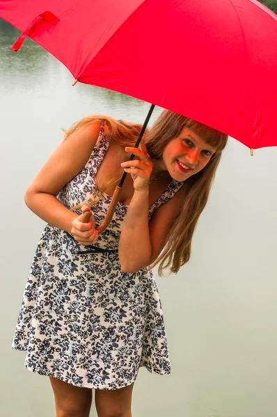 Девушка с красным зонтиком возле пруда — стоковое фото