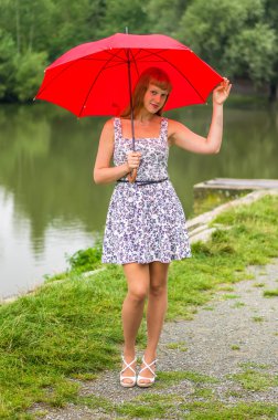 Gölet yakınındaki kırmızı şemsiye ile genç bayan