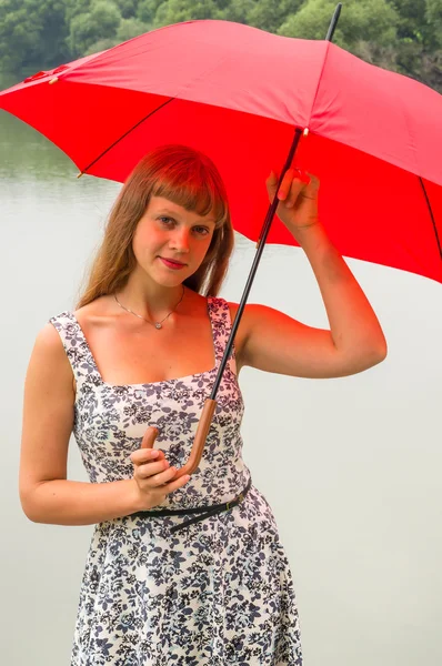 Junge Dame mit rotem Regenschirm in Teichnähe — Stockfoto