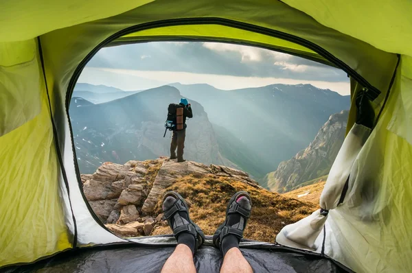 View from inside a tent on the young man on a rock — Stock Photo, Image