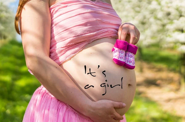 Живіт вагітної дівчини в квітучому фруктовому саду — стокове фото