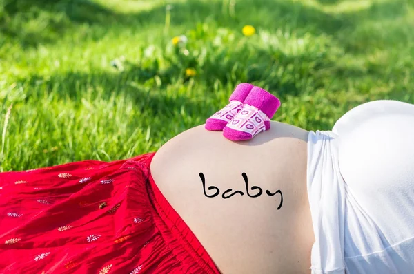 怀孕的年轻女孩，在花园的草地上 — 图库照片