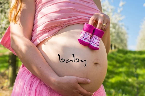 Ventre d'une fille enceinte dans le jardin de fruits en fleurs — Photo