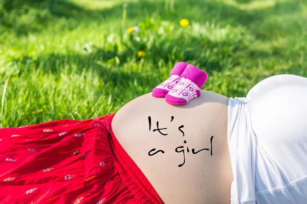 怀孕的年轻女孩，在花园的草地上 — 图库照片