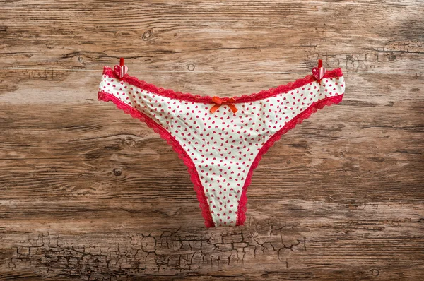 Panties with red lace attached to rope with clothespins — Stock Photo, Image