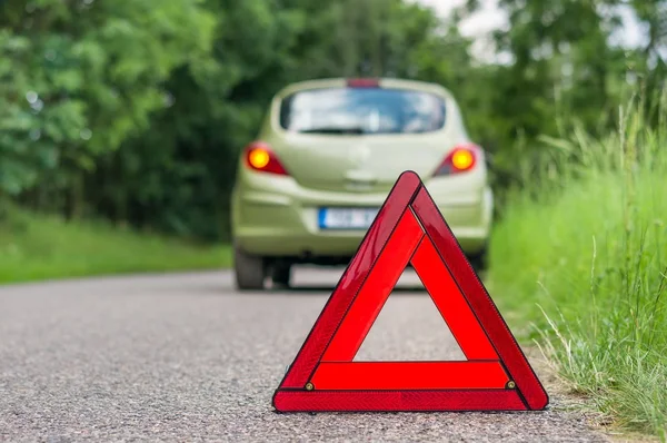 Red warning triangle and broken car on the road — Stock Photo, Image