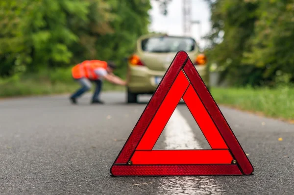 Driver in reflective vest changing tire — Stock Photo, Image