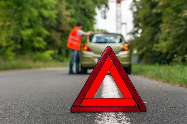 Broken car on the road and warning triangle