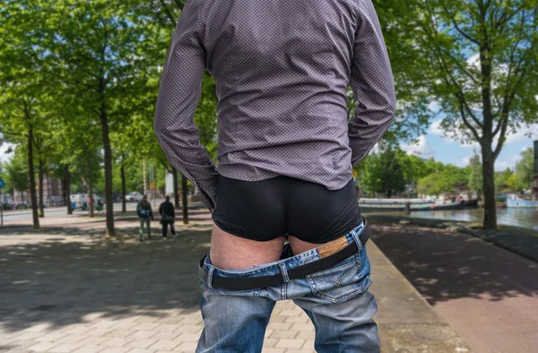 Standing man peeing to a street in big town — Stock Photo, Image