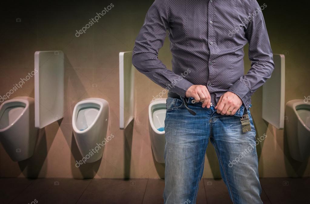 A woman wearing white jeans is pissing in the public toilet