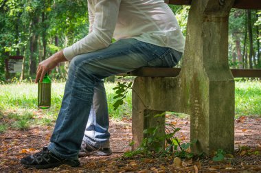 Yalnız sarhoş adam bankta oturan bira şişesi ile