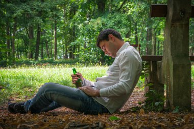Sarhoş adam yere yakın tezgah üzerinde bir bira şişesiyle yatıyor
