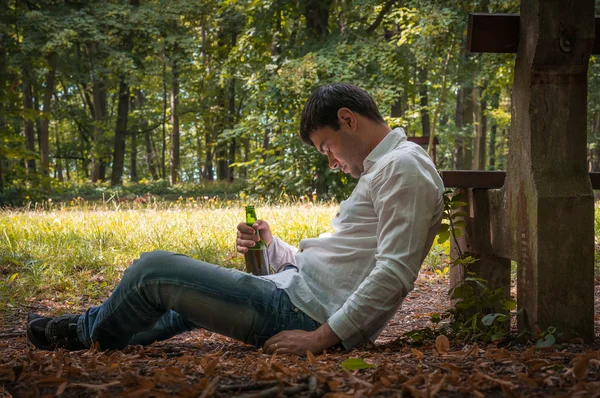 맥주 병으로 벤치 근처 바닥에 취한 사람 거짓말 — 스톡 사진