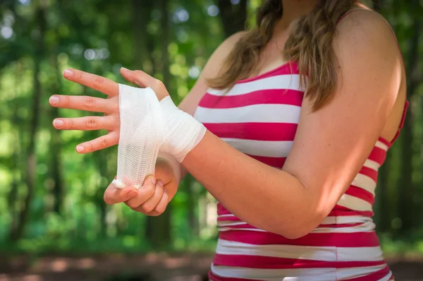 Mujer que se aplica vendaje en la mano después de una lesión —  Fotos de Stock