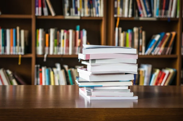 Pile of books in a library and bookshelf — Stock Photo, Image