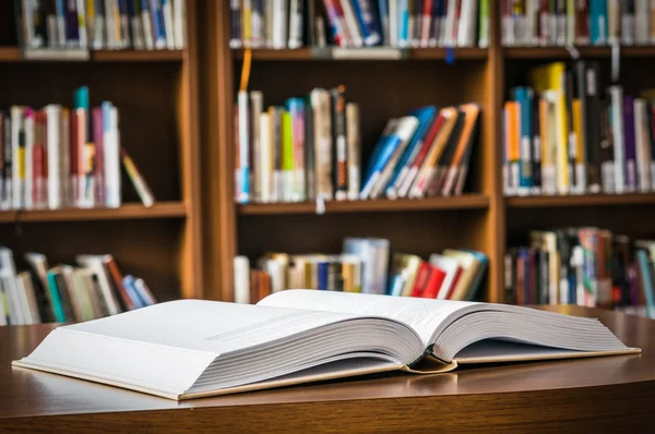 Open book on the table in a library and bookshelf — Stock Photo, Image