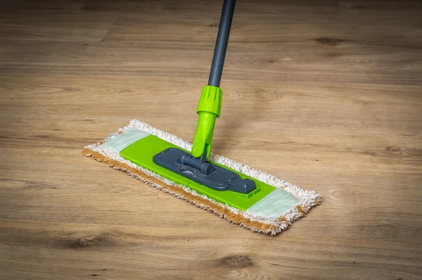 Woman with mop mopping wooden laminate floor
