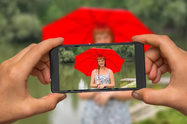 携帯電話と赤い傘を持つ女性の写真を撮る — ストック写真