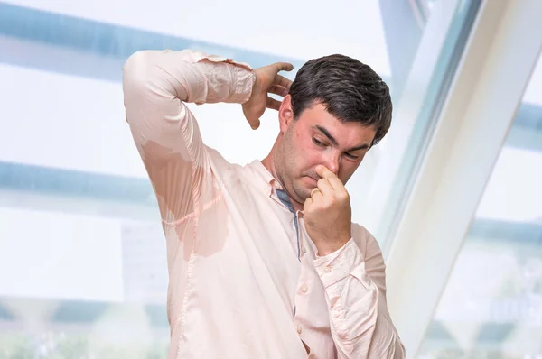 Man met zweten onder oksel wringt neus met vingers — Stockfoto