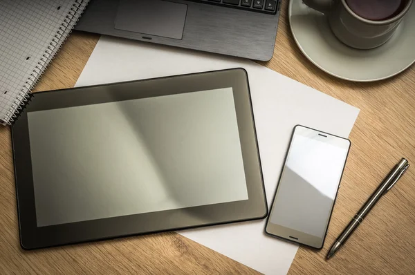 Tablet, telefone celular, caneta, laptop e xícara de café na mesa — Fotografia de Stock