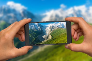 Cep telefonu ile dağların ve buzulun fotoğrafını çekmek