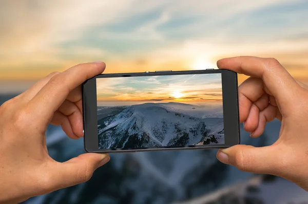 携帯電話で山の夕日の写真を撮る — ストック写真