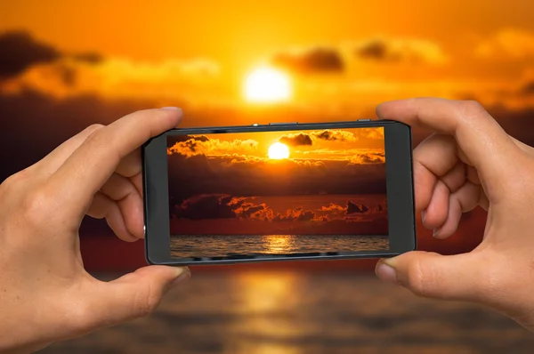 Toma de fotos de la puesta del sol y el mar con teléfono móvil — Foto de Stock