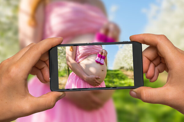 Taking photo of belly of a pregnant girl with mobile phone