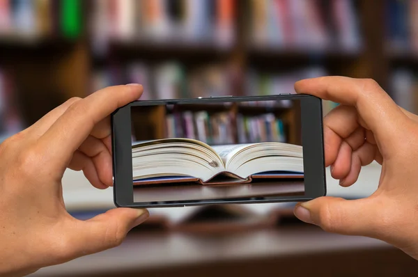 Aufgeschlagenes Buch in Bibliothek mit Handy fotografieren — Stockfoto