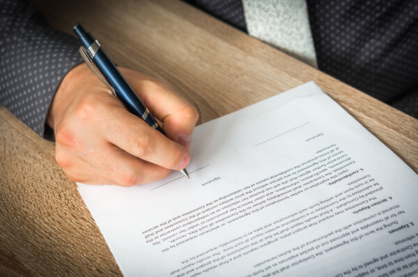 Бизнесмен подписывает контракт на заключение сделки
