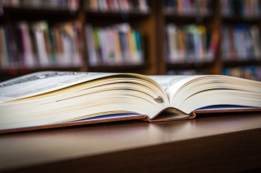 Bir kütüphane ve kitaplık masada açık kitap