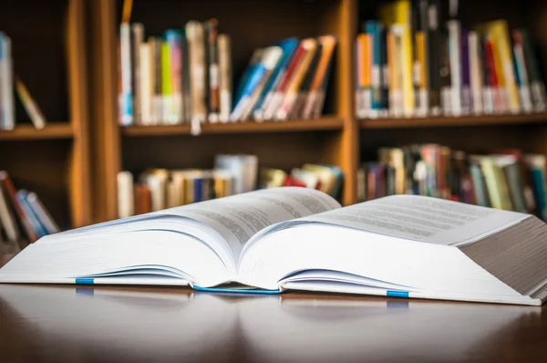 Open book on the table in a library and bookshelf — Stock Photo, Image