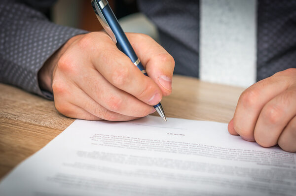 Бизнесмен подписывает контракт на заключение сделки
