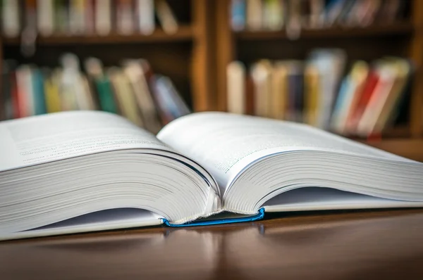 Open book on the table in a library and bookshelf — Stock Photo, Image