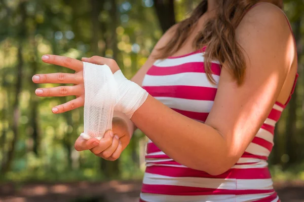 Mujer que se aplica vendaje en la mano después de una lesión —  Fotos de Stock