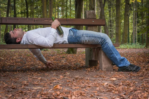 Hombre borracho dormido en un banco del parque con botellas de cerveza — Foto de Stock