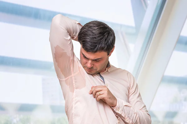 Man with hyperhidrosis sweating under armpit in office — Stock Photo, Image