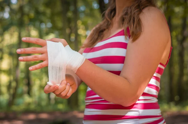 Mujer que se aplica vendaje en la mano después de una lesión — Foto de Stock