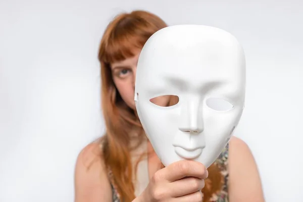 Mysterious woman cover her face behind anonymous white mask