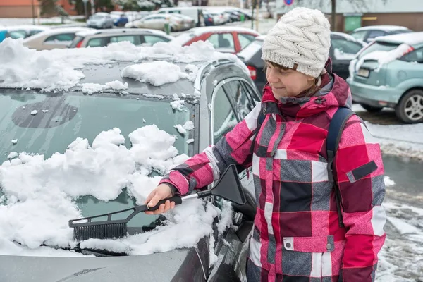 Kvinnelig Sjåfør Vasker Snø Med Pensel Fra Bilfrontruten – stockfoto