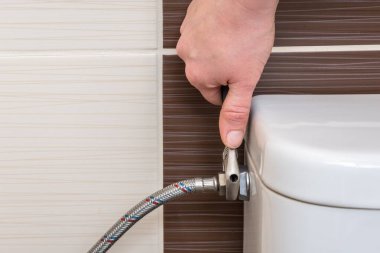 Tesisatçı İngiliz anahtarı kullanarak tuvalet sifonunu tamir ediyor.