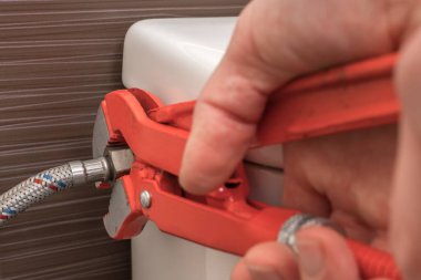 Tesisatçı İngiliz anahtarı kullanarak tuvalet sifonunu tamir ediyor.