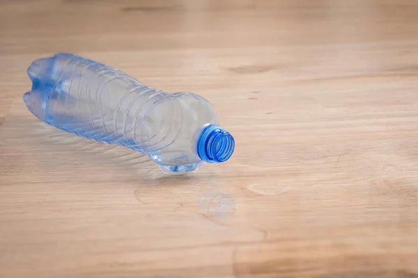 Verschüttetes Wasser Und Umgestürzte Plastikflasche Auf Holzlaminatboden — Stockfoto
