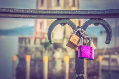 Love padlocks on a railing in the harbor on blurred lighthouse b clipart