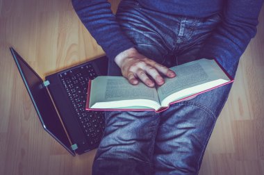 Young man sitting on the floor in living room and reading a book