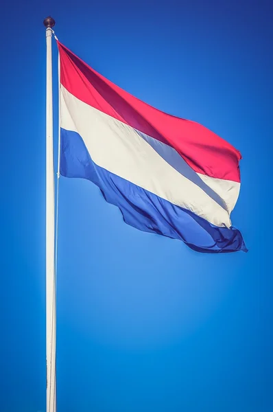 Netherlands flag on the blue sky - retro and vintage style — стокове фото