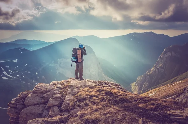 Young man standing on a rock and looking at a beautiful mountain — Stock Photo, Image